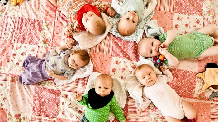 Seks babyer der ligger på et tæppe