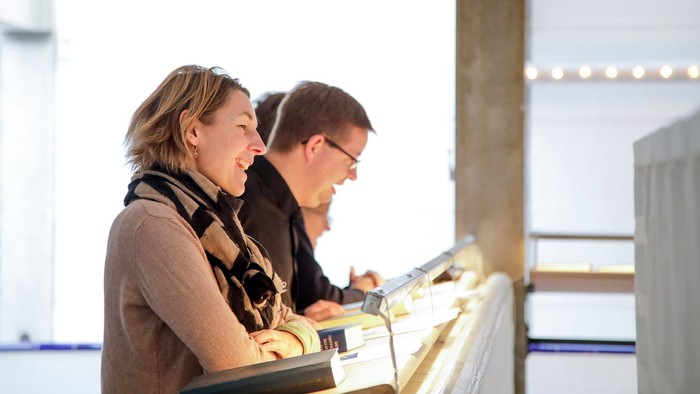 To mennesker sidder ved bord og ser på en laptop.