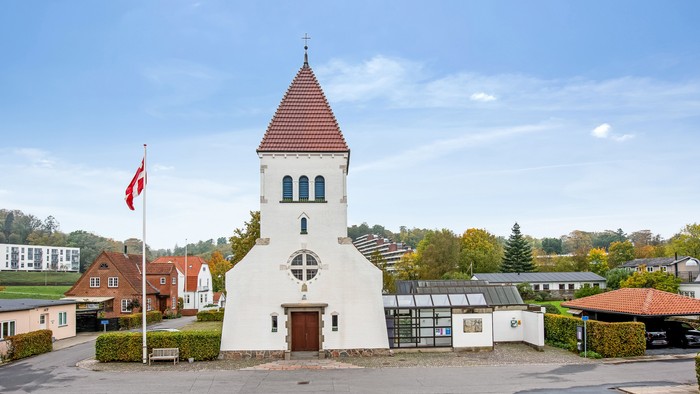 En lille kirke med tårn og en canadisk flag i forgrunden