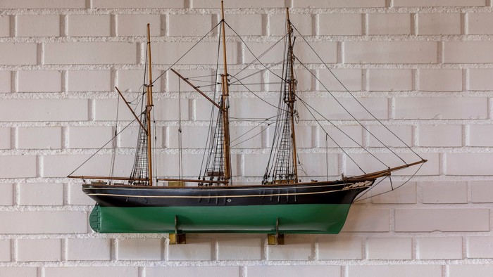 Et smukkt modelleret skib monteret på en hvid mursten.