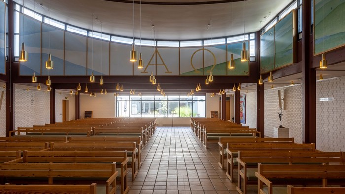 En moderne kirkeindretning med træbænke og hængende lygter