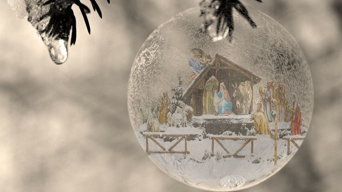 Ein Weihnachtsbaumzweig mit einer Kugel, die eine Krippe zeigt