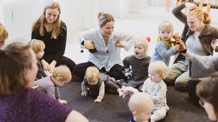 En gruppe børn og voksne sidder på gulvet og spiller.
