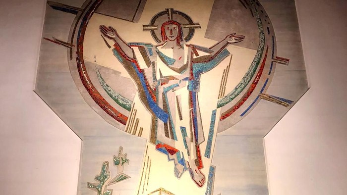 Ein religiöses Wandgemälde zeigt eine Figur mit ausgebreiteten Armen, umgeben von einem kreisförmigen Muster.