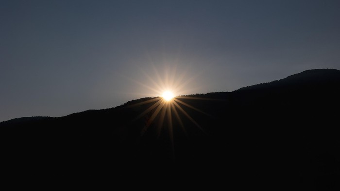 Aufgehende Sonne hinter einem dunklen Berg