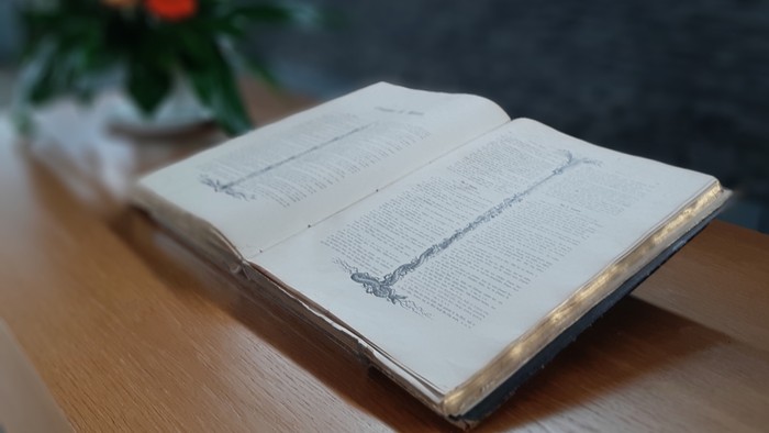 Offenes Buch auf Holzoberfläche neben Blumenstrauß