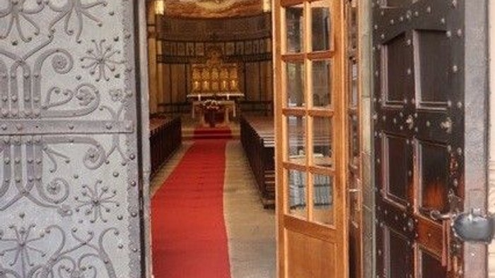 Offene Holztür mit rotem Teppich dahinter