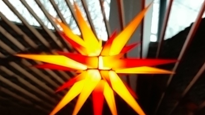 Leuchtende orangefarbene Sterndekoration an der Decke