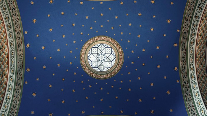Kompliceret blåt loft med stjernemønstre og centralt cirkulært vindue.