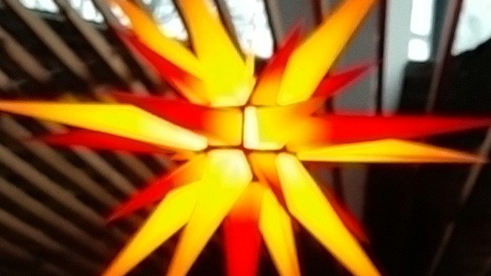 Leuchtende orangefarbene Sterndekoration an der Decke