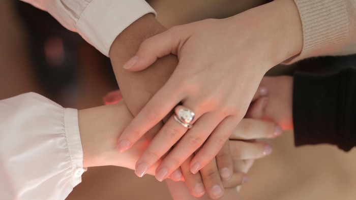 En person holder en andet persons hånd, der bærer et bryllupsring.
