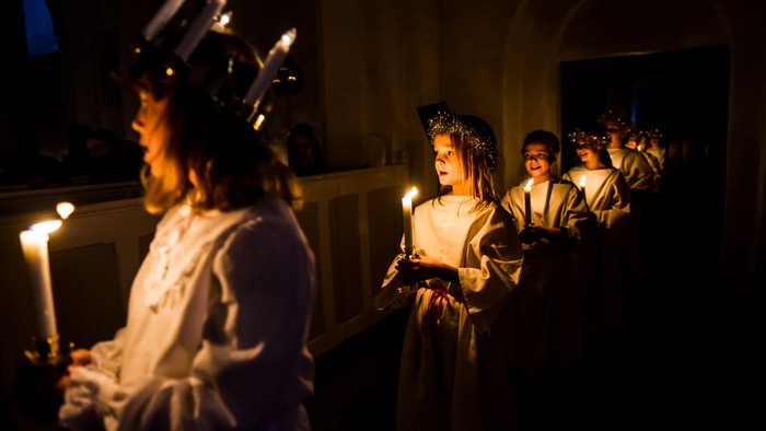 En gruppe børn i festlige kredenceremonier med lysekeruber og lysstaker
