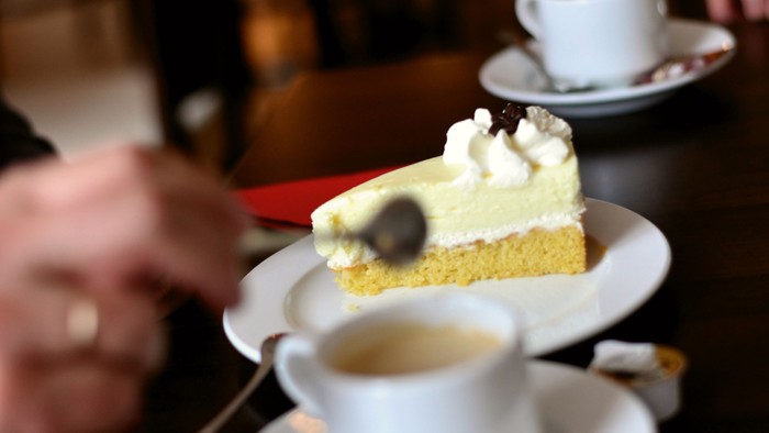 Eine Person genießt ein Stück Kuchen und Kaffee in einem Café.