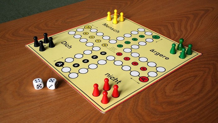 Ein Gesellschaftsspielbrett mit Spielsteinen und Würfeln auf einem Holztisch