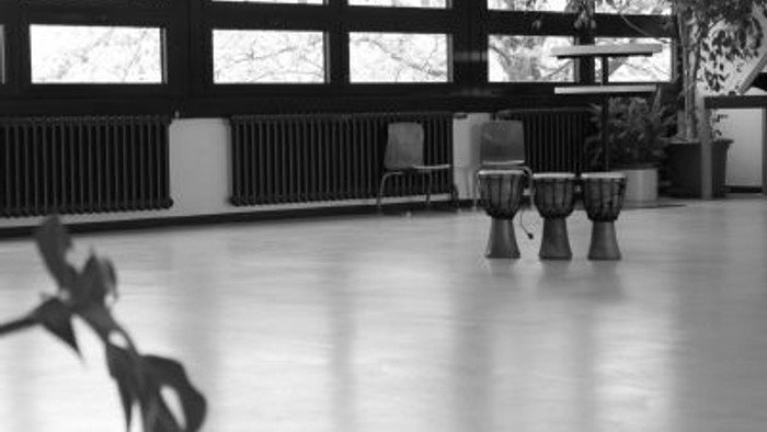 Ein Raum mit großen Fenstern und drei Djembes in der Mitte.