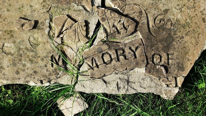 Verwitterter Grabstein mit der Inschrift „Zum Gedenken an“