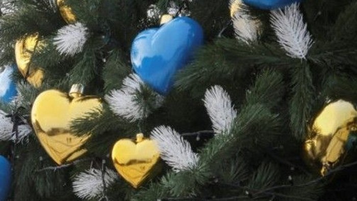 Juletræ pyntet med blå og guld hjerteornamenter og hvide fyrrekogler.