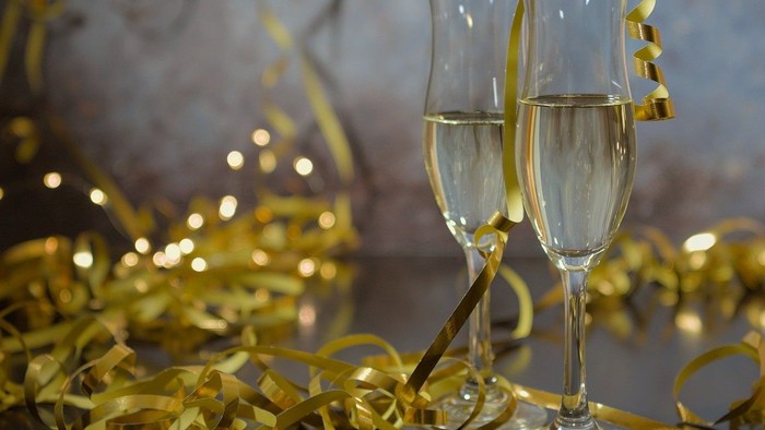 Zwei Champagnergläser mit goldenen Konfettibändern