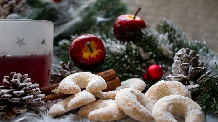 Weihnachtlich gedeckter Tisch mit Plätzchen, Äpfeln und Dekorationen