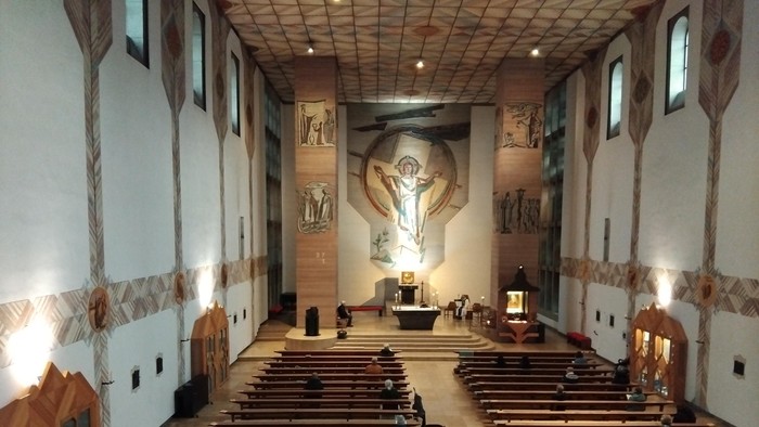 Modern gestaltete Kirche mit Holzpaneelen und großem Kreuz an der Wand