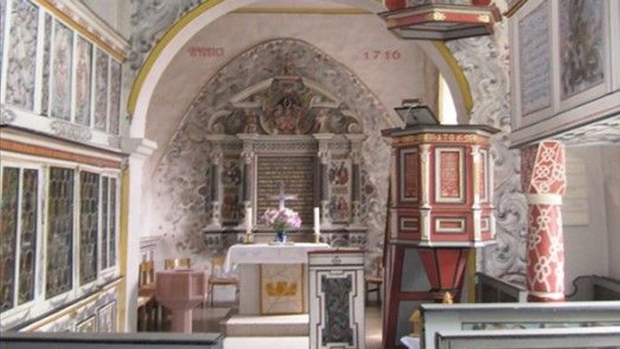 Die Kirche hat einen schönen Altar und hohe Decken.
