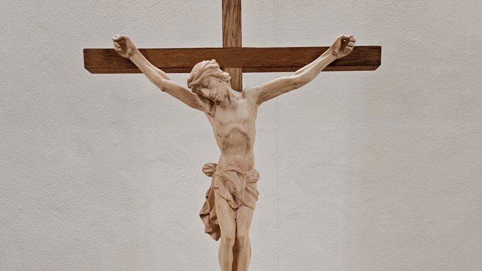Holzskulptur von Jesus am Kreuz auf hölzernem Sockel