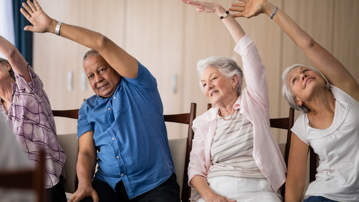 Ältere Menschen machen gemeinsam Gymnastik in einem Raum