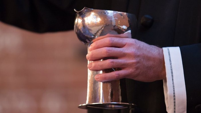 En person holder en stor, blank metalpokal.