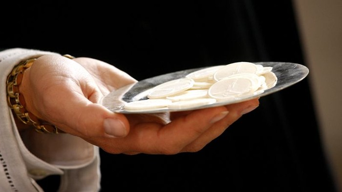 Hånd holder en smuk, hvid skive med blomstermotiv.