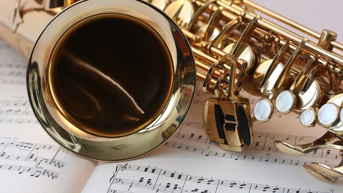 Et blæseløg med guldfarvet metal og sorte toner ligger på noter.