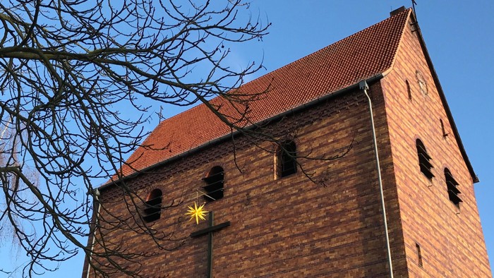Ein Ziegelbau mit spitzem Dach und Kreuz unter einem klaren blauen Himmel