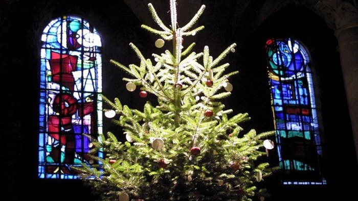 En juletree foran farverige vinduer