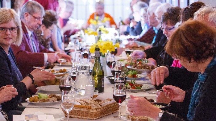 En gruppe af personer sidder ved et langt bord og spiser.