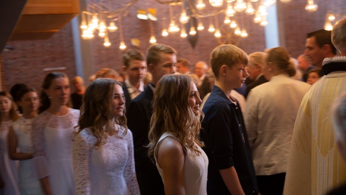 En gruppe af festdeltagere danser og samler sig i et lysende og indelukket rum.