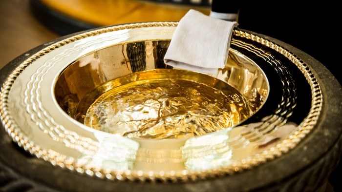 Gylden skål med klæde indeni, placeret på en udsmykket overflade.