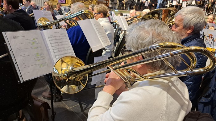 Eine Gruppe von Musikern spielt in einem Saal verschiedene Blasinstrumente.