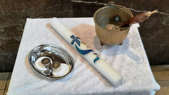 Auf dem Tisch stehen eine Schale, ein weißes Objekt mit Schrift und ein kleines Becken mit Wasser.