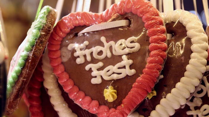 Herzförmiger Kekse mit Zuckerguss-Beschriftung *„Frohes Fest“* und mit Süßigkeiten verziert.