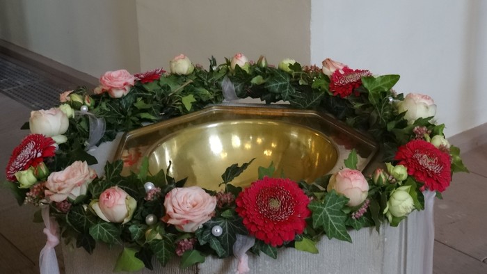 Eleganter Blumenkranz, der eine goldene Urne auf einer drapierten Fläche umgibt.