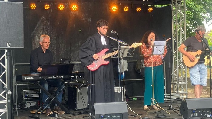 Eine Band spielt auf einer Bühne unter einem Zelt