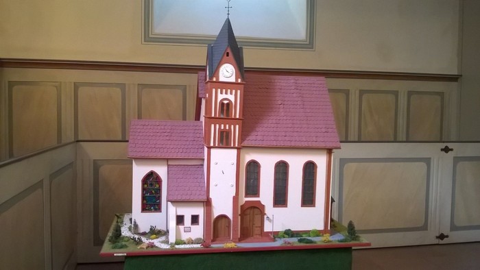 Ein Miniaturmodell einer Kirche mit rosa Dach und Uhrturm.