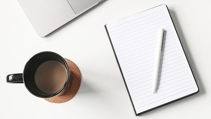 Bureau med laptop, notatbog, pen, mobiltelefon, kaffe og planter