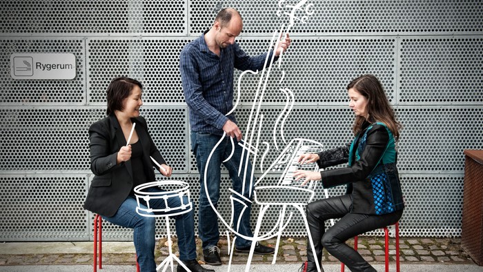 En gruppe af tre personer spiller på en metalstol og to redskaber på gaden.