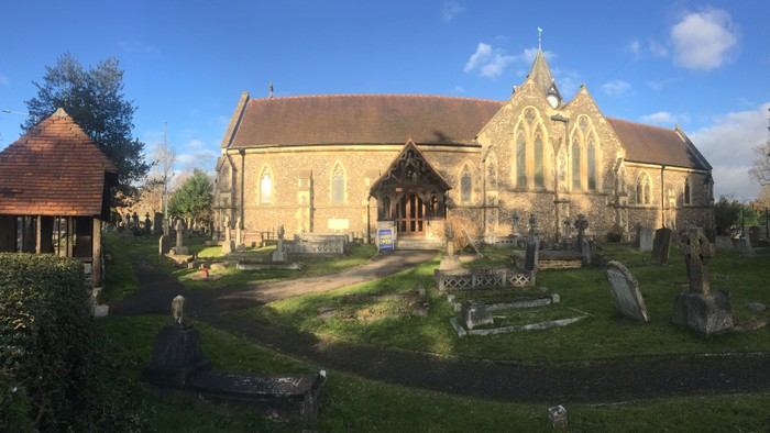 Church with graveyard and surrounding greenery under a blue sky