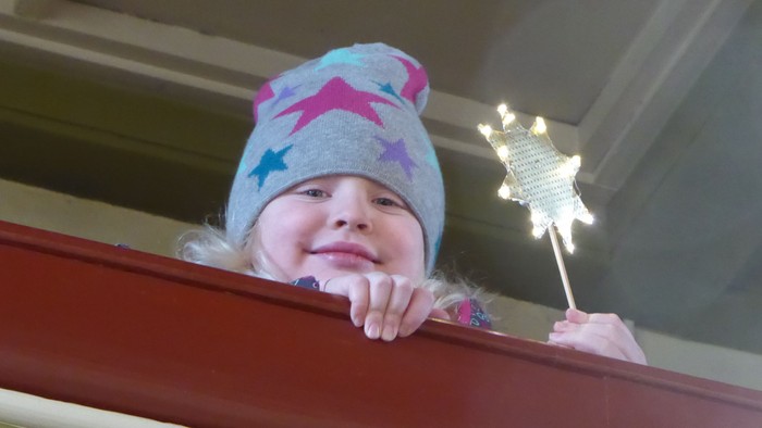 Ein Kind mit einer sterngemusterten Mütze hält einen Sternenzauberstab.