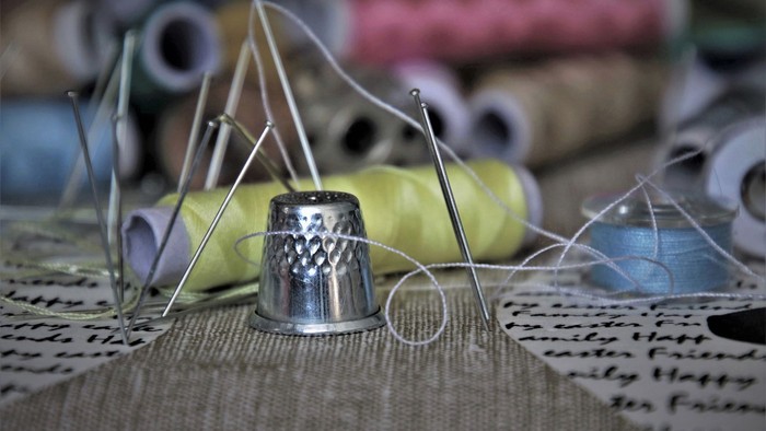 Näheutensilien wie Nadeln, Faden und Nadelkissen auf einem Tisch