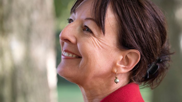 Kvinde i rød frakke, der smiler udendørs.