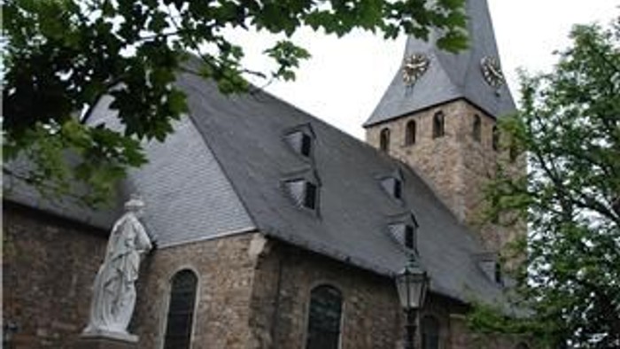 Altes Kirchengebäude mit hohem Turm und Statue davor