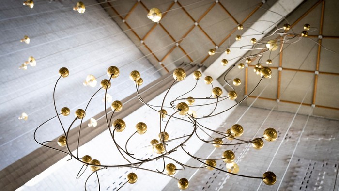 Elegant lysekrone med gyldne sfæriske lys i en kunstnerisk, buet opsætning.