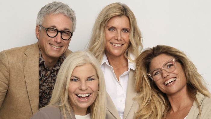 Fire smilende personer, der poserer sammen, sandsynligvis i en professionel sammenhæng.